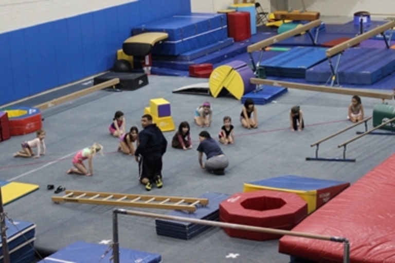Children practice gymnastics skills in a gym.
