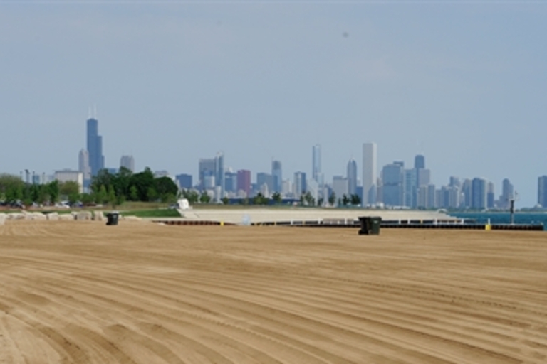 Smooth, raked sand beach with the Chicago skyline in the distance.