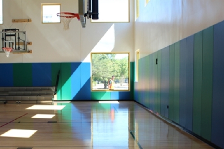 Indoor basketball court with sunlight streaming through windows.