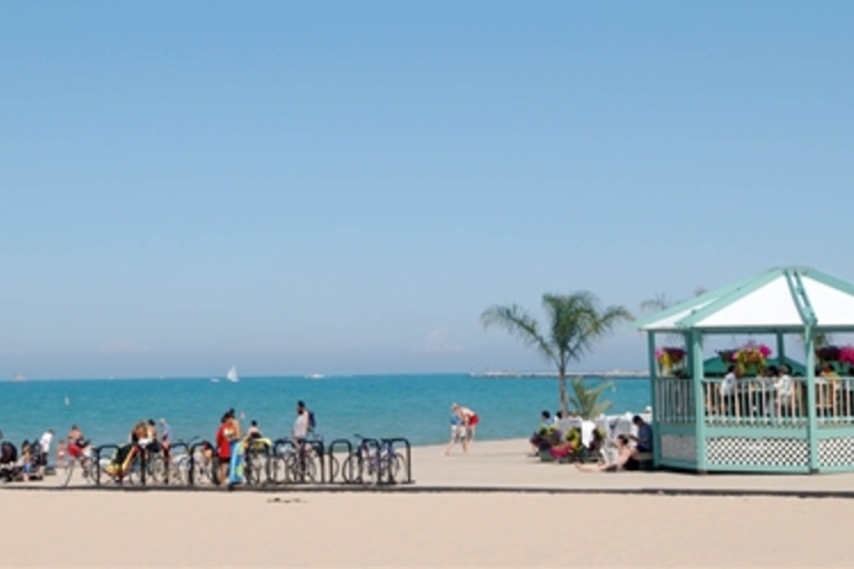 Beachgoers enjoy a sunny day at the beach with a gazebo.