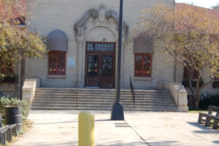 Front entrance of a light-colored building with stairs and decorative awnings.