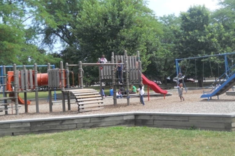 Children play on a playground with swings, slides, and climbing structures.
