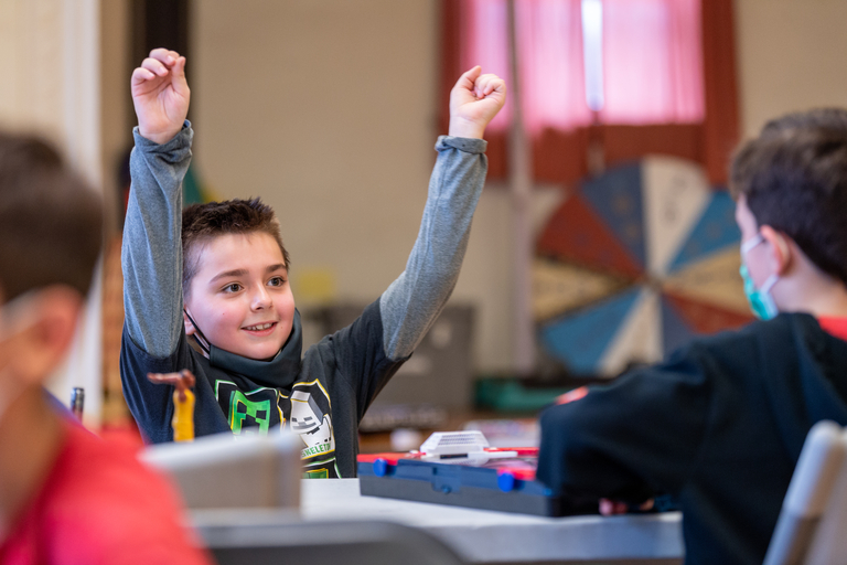 Excited boy with arms raised.