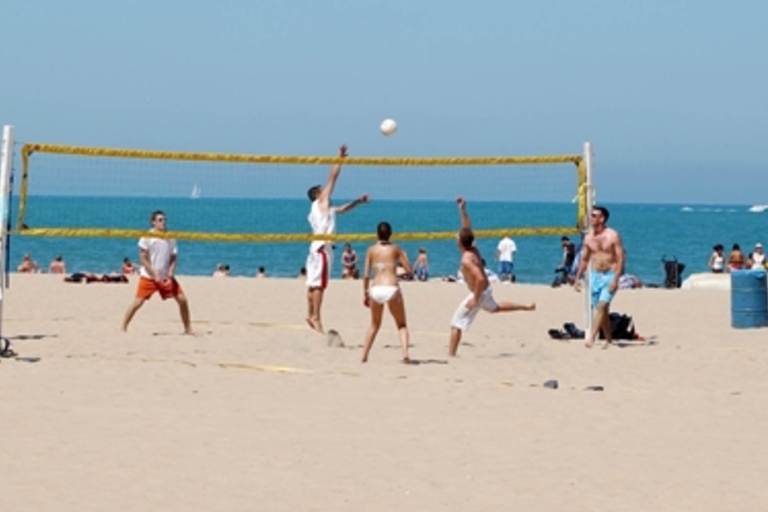 People playing beach volleyball on a sunny day.
