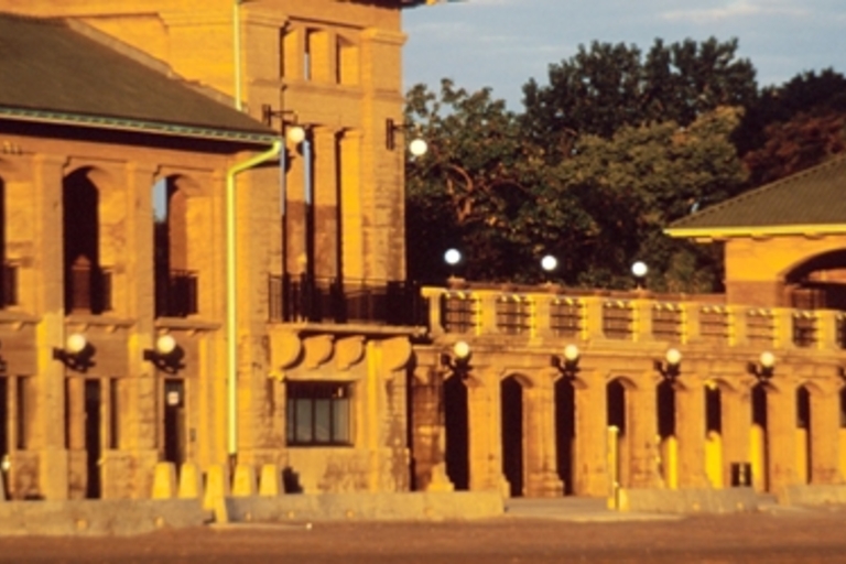 Exterior of a weathered, light brown stone building with arched openings.