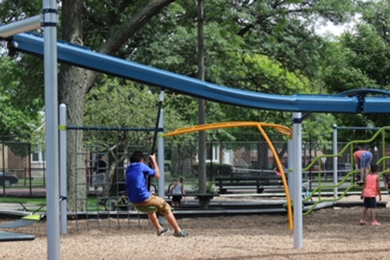 Children play on a playground with a roller slide and zip line.

