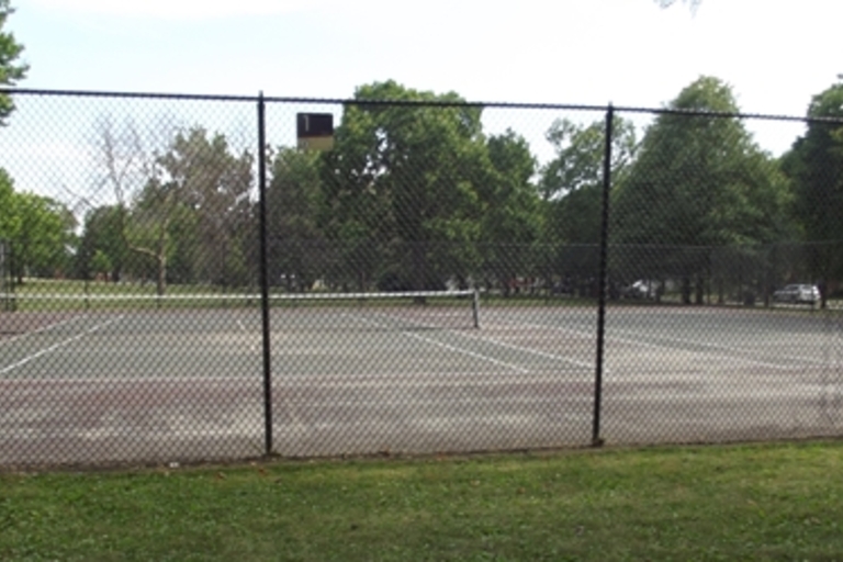 Fenced tennis courts on a sunny day.