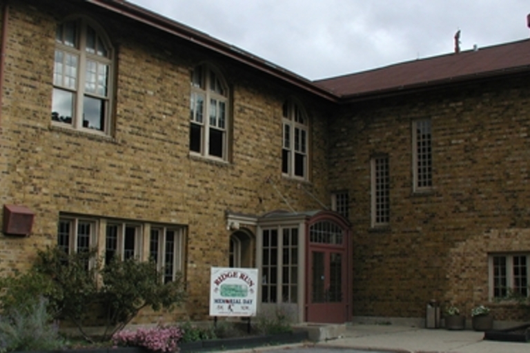 Tan brick building with arched, multi-paned windows.