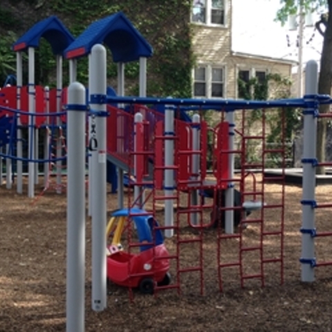 Red, white, and blue playground equipment on wood chips.