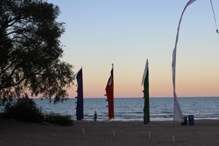 Colorful flags on a beach at sunset.