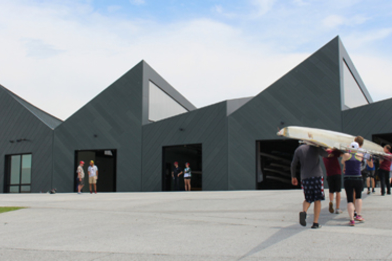 Crew team carrying a scull toward boathouse.
