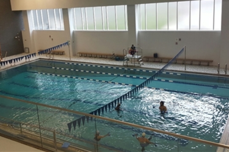 Indoor pool with several people swimming.