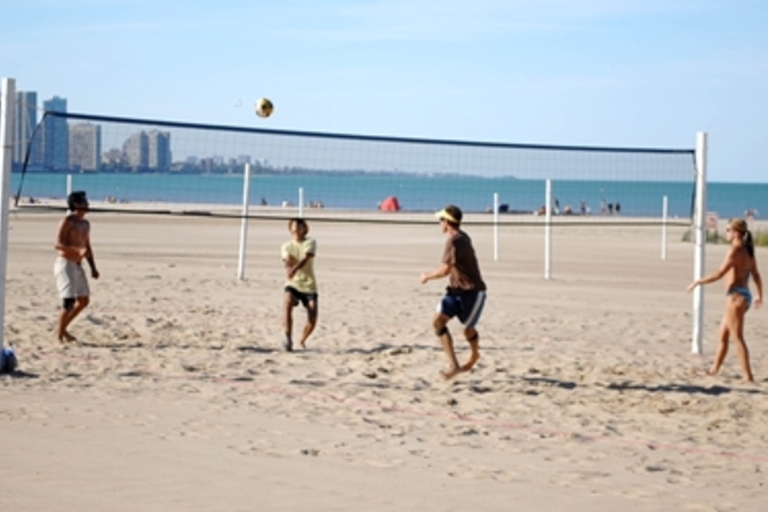 People playing beach volleyball on a sunny day.
