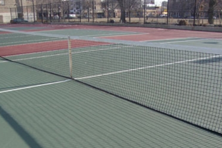 Empty green and red tennis courts on a sunny day.