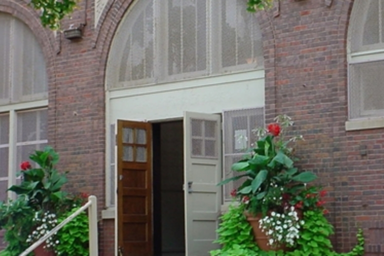 Open doorway of a brick building with potted plants.