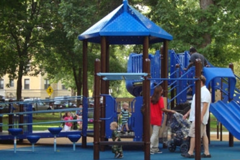Children and adults play on a blue and brown playground set.
