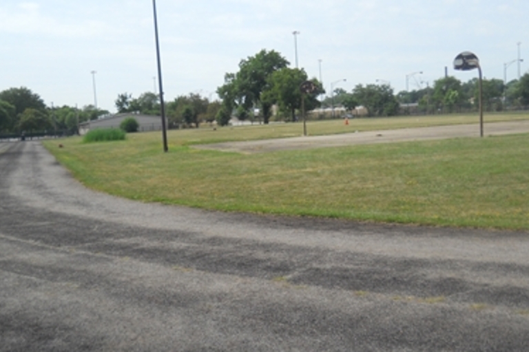 Paved path curves around a park with basketball court.
