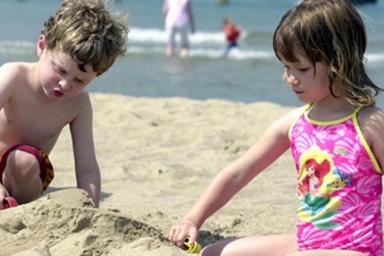 Two young children playing in the sand at the beach.
