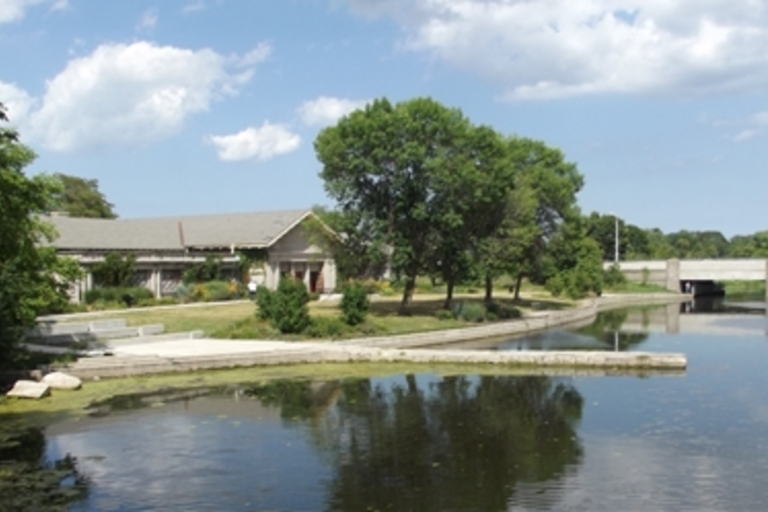 Park building by the pond with bridge in background.