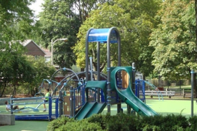 Children play on a playground with green and blue equipment.