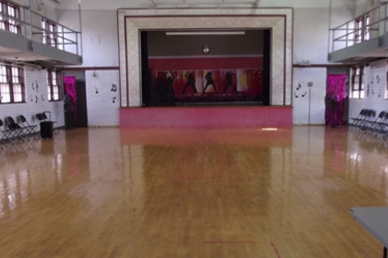 Empty dance hall with a stage and chairs.