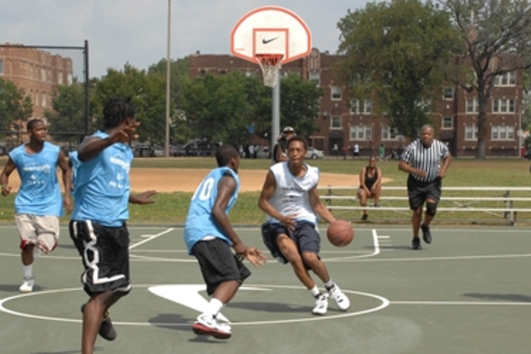 Outdoor basketball game in action on a sunny day.