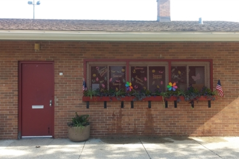 Red door and decorated window of brick building.