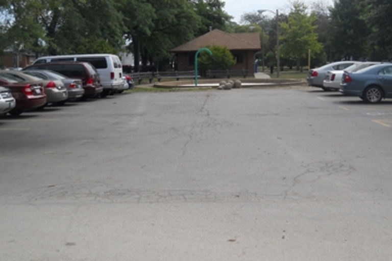 Empty parking lot with a small park building in the background.