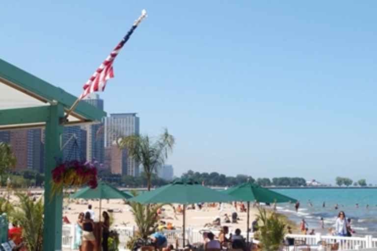 Beachgoers relax on a sunny beach with a city skyline in the distance.