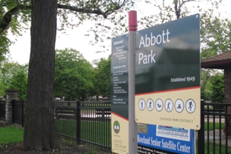 Abbott Park sign with trees and part of a building in the background.
