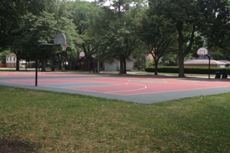 Outdoor basketball court with red and gray surface.