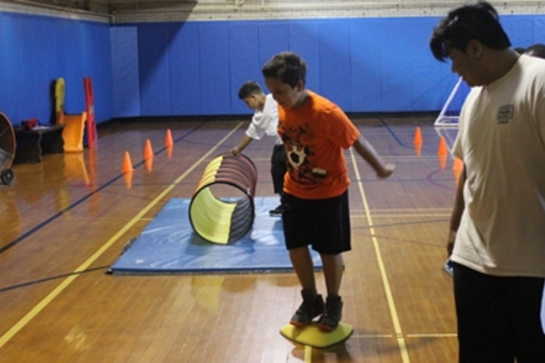 Children playing on gym equipment in a gymnasium.