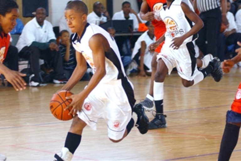 Youth basketball player dribbles ball down court.
