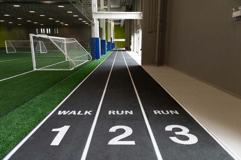Indoor running track with "walk" and "run" lanes beside an indoor soccer field.