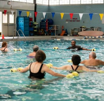 People participate in a water exercise class using water weights.