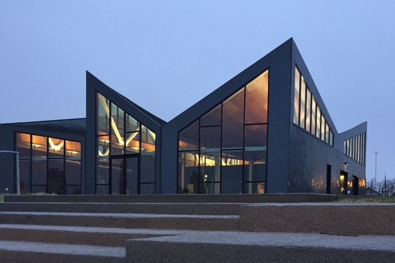 Modern building with large windows, illuminated at dusk. Concrete steps in foreground.
