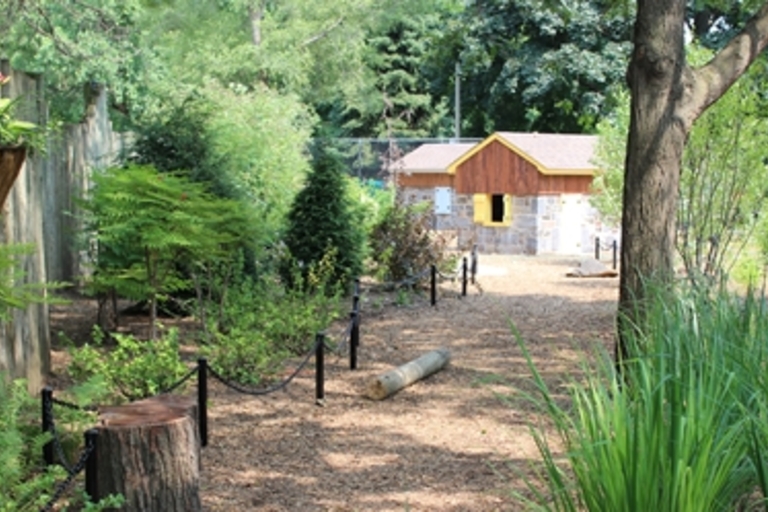 Path leading to small zoo enclosure building surrounded by greenery.