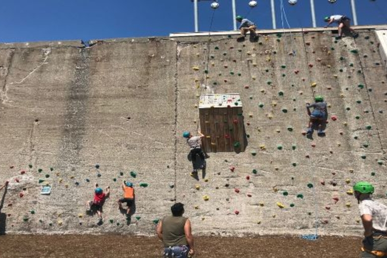 Children climb a rock climbing wall.