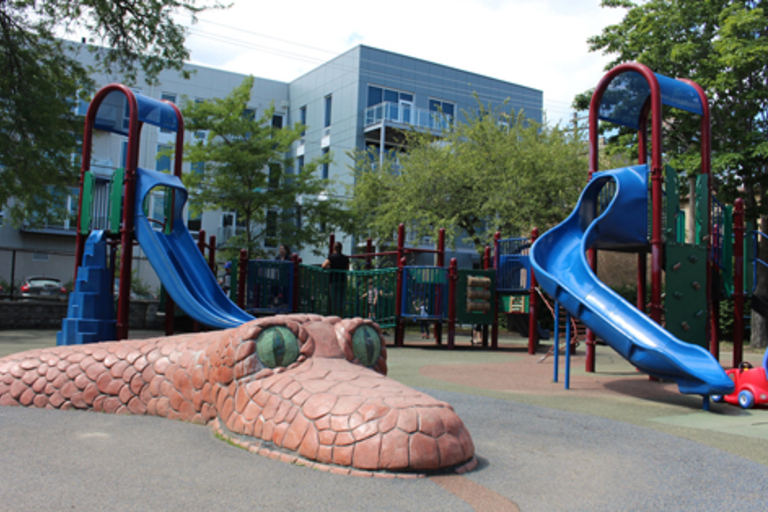 Colorful playground with slides and a large snake sculpture.
