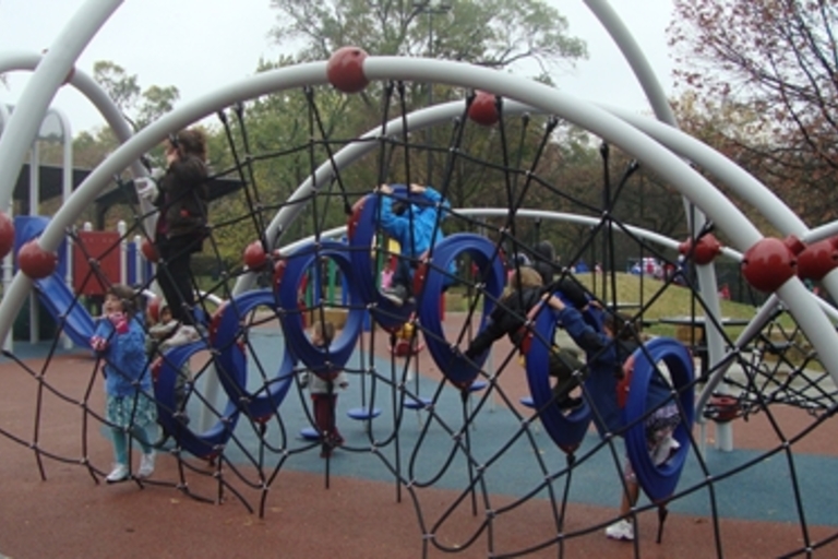 Children climb on a playground jungle gym.
