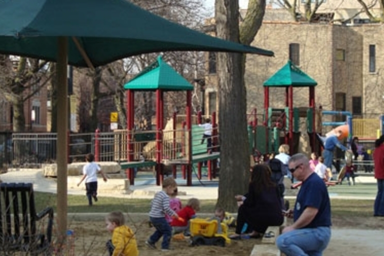 Children play on playground equipment in a park.