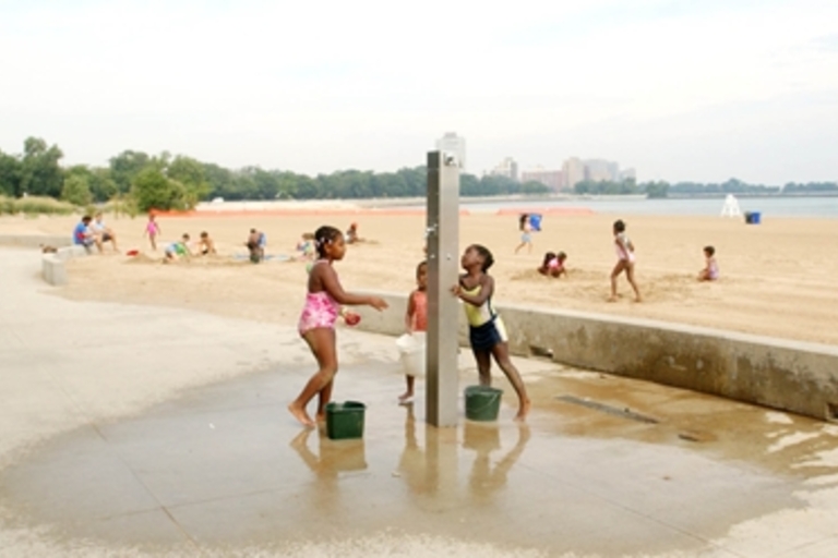 Children play at a beachside shower.
