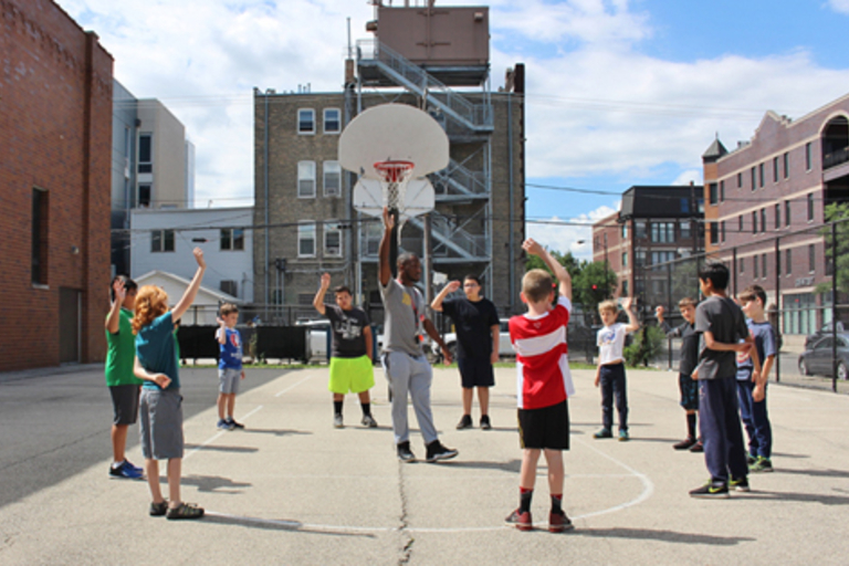 Children playing basketball on an outdoor court.