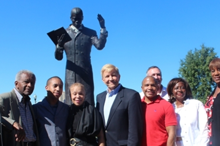 Group photo in front of a statue of a reading man.