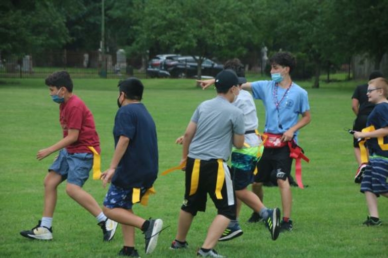 Children playing flag football in a park.
