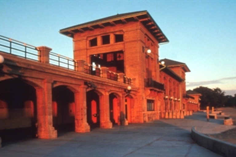 Sunrise illuminates a beachside pavilion with arched walkways.
