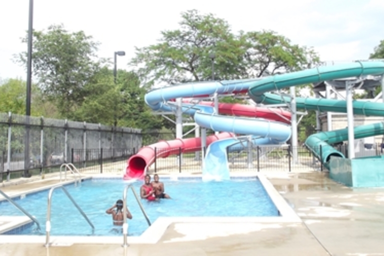 Kids play in a pool at the bottom of a colorful waterslide.
