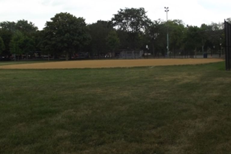 Empty baseball field with dirt infield and grassy outfield.