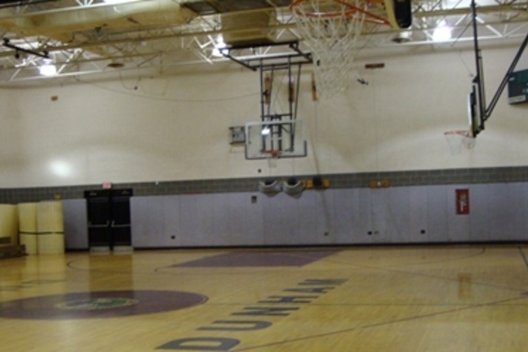 Empty high school gymnasium with basketball hoops.