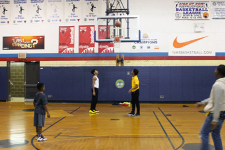 Young basketball players practice shooting hoops in a gym.